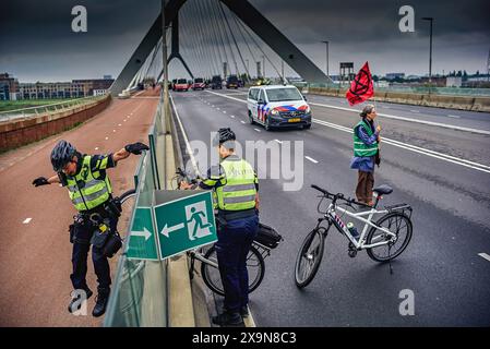 La police tente de donner accès à la piste cyclable adjacente. Des militants du groupe d'action extinction Rebellion (XR) bloquent le pont de la ville (de Overstuk) le 1er juin. C'est l'une des actions contre l'arrivée possible d'une nouvelle centrale électrique à Nimègue qui fonctionnera au gaz pendant des années. XR veut que cela cesse « immédiatement ». Le maire de Nimègue, Hubert Bruls, a autorisé une marche de protestation de XR à travers le centre de Nimègue et a annoncé à l'avance qu'il prendrait des mesures si l'un des ponts était bloqué. pont de train est deux ponts de ville pour la circulation. Le pont Waal (1936) et l'Overstee Banque D'Images