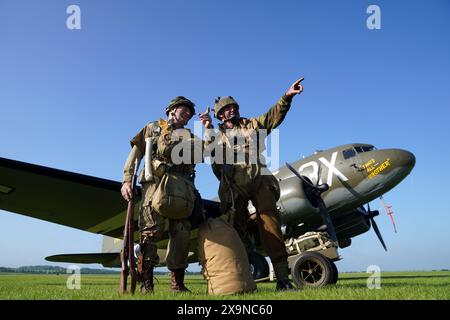 Les reconstituteurs Mark Bailey (à gauche) et Neil Hannant posent devant un Douglas C47, connu sous le nom de Dakota dans la Royal Air Force et les services du Commonwealth, qui est devenu l'avion de transport le plus connu au monde et a été largement utilisé par les Alliés pendant la seconde Guerre mondiale, lors de l'IWM Duxford Summer Air Show dans le Cambridgeshire. Date de la photo : dimanche 2 juin 2024. Banque D'Images