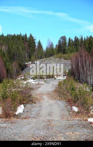 Énorme tas de gravier dans la forêt avec petite route. Banque D'Images