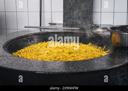 Les carottes jaunes sont cuites dans un chaudron pour cuisiner le pilaf ouzbek asiatique dans la cuisine à Tachkent en Ouzbékistan Banque D'Images