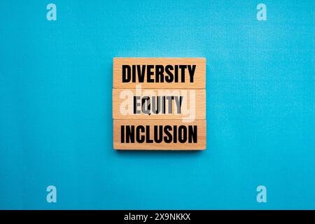 Diversité, équité et inclusion mots écrits sur bloc de bois avec fond bleu. Symbole DEI DE diversité conceptuelle, d'équité et d'inclusion. Copier l'espace. Banque D'Images