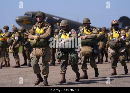 Les parachutistes à canopée ronde se préparent à charger sur un avion Douglas C47, connu sous le nom de Dakota, qui est devenu l'avion de transport le plus connu au monde et a été largement utilisé par les Alliés pendant la seconde Guerre mondiale lors de l'IWM Duxford Air Show dans le Cambridgeshire, alors qu'ils traversent la Manche pour continuer les commémorations du 80e anniversaire du jour J. Date de la photo : dimanche 2 juin 2024. Banque D'Images