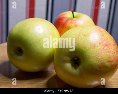 Pommes mûres sur bois. Pommes avec un mélange de teintes rouges et vertes sur fond de bois, parfaites pour les thèmes liés à la nourriture. Banque D'Images