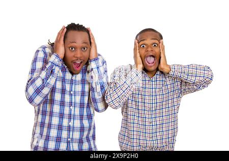 Gros plan portrait deux beaux jeunes hommes regardant choqués, surpris par l'incrédulité, les mains sur la tête regardant votre appareil photo, fond blanc isolé. Banque D'Images