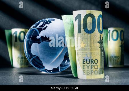Globe bleu avec cent billets en euros sur fond sombre Banque D'Images