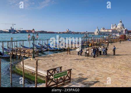 Venise, Italie - 20 mars 2024 - Groupe de touristes et de gondoles sur la promenade riveraine de Riva degli Schiavoni. Banque D'Images