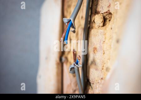 Câble d'alimentation électrique endommagé à l'intérieur du trou mural. Banque D'Images