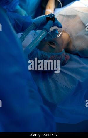 Anesthésiste appliquant une machine d'anesthésie à une patiente en salle d'opération Banque D'Images