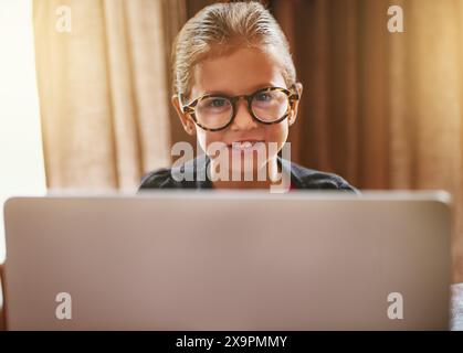 Maternelle, enfant et apprentissage sur ordinateur portable à la maison avec bonheur d'étudier dans l'éducation en ligne. Excité, enfant et portrait à l'ordinateur avec ai cours Banque D'Images