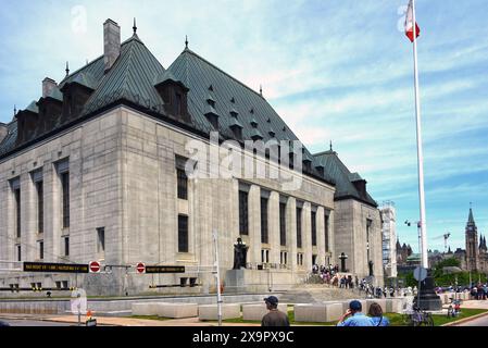 Ottawa, Canada - 1er juin 2024 : un groupe de personnes s'alignent pour voir l'intérieur de l'édifice de la Cour suprême dans le cadre de l'événement portes ouvertes annuel qui permet aux gens de voir l'intérieur et d'en apprendre davantage sur les divers édifices de la région. La tour de la paix est visible sur la droite. Banque D'Images