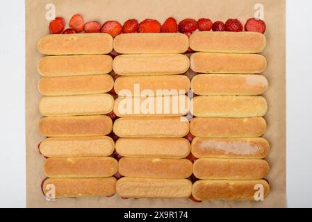 Vue de dessus des rangées de biscuits savoiardi sur les fraises. Préparer le gâteau tiramisu à la maison. Banque D'Images