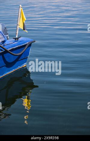 Poupe d'un bateau bleu avec un drapeau jaune reflété dans l'eau calme avec de petites vagues, concept pour les vacances d'été, sports nautiques et activités de loisirs, larg Banque D'Images