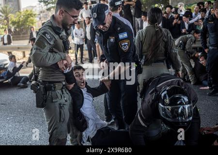 Bnei Brak, Israël. 02 juin 2024. Les policiers israéliens éloignent les manifestants ultra-orthodoxes qui bloquent une route à Bnei Brak, lors d’une manifestation contre d’éventuels changements de lois exemptant les hommes ultra-orthodoxes de la conscription militaire. Crédit : Ilia Yefimovich/dpa/Alamy Live News Banque D'Images