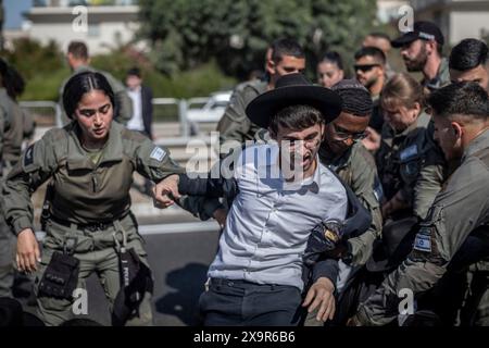 Bnei Brak, Israël. 02 juin 2024. Les policiers israéliens éloignent les manifestants ultra-orthodoxes qui bloquent une route à Bnei Brak, lors d’une manifestation contre d’éventuels changements de lois exemptant les hommes ultra-orthodoxes de la conscription militaire. Crédit : Ilia Yefimovich/dpa/Alamy Live News Banque D'Images