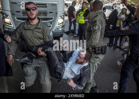 Bnei Brak, Israël. 02 juin 2024. Les policiers israéliens éloignent les manifestants ultra-orthodoxes qui bloquent une route à Bnei Brak, lors d’une manifestation contre d’éventuels changements de lois exemptant les hommes ultra-orthodoxes de la conscription militaire. Crédit : Ilia Yefimovich/dpa/Alamy Live News Banque D'Images