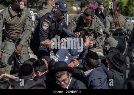 Bnei Brak, Israël. 02 juin 2024. Les policiers israéliens éloignent les manifestants ultra-orthodoxes qui bloquent une route à Bnei Brak, lors d’une manifestation contre d’éventuels changements de lois exemptant les hommes ultra-orthodoxes de la conscription militaire. Crédit : Ilia Yefimovich/dpa/Alamy Live News Banque D'Images