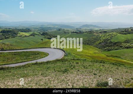 Une route de campagne sinueuse près de Volterra en Toscane, Italie par une journée ensoleillée avec de belles vues classiques sur les collines et la campagne et les champs. Banque D'Images