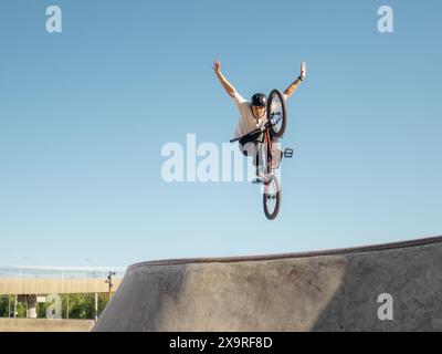 Cycliste BMX volant et faisant Stunt pas de main dans le quart de tuyau. Athlète freestyler de BMX qualifié sautant par-dessus le quart de rampe et faisant le tour aérien No H. Banque D'Images