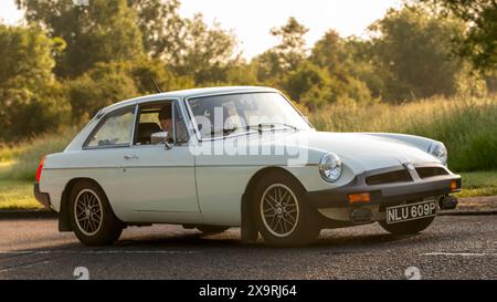 Stony Stratford, Royaume-Uni - 2 juin 2024 : 1976 voiture blanche MG B GT conduisant sur une route de campagne britannique Banque D'Images