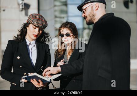 Trois jeunes entrepreneurs sont engagés dans une discussion collaborative, tenant des documents et travaillant ensemble au milieu de l'architecture de la ville. Banque D'Images
