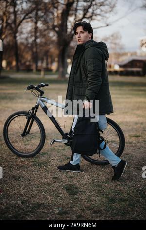 Homme occasionnel marchant à vélo dans un parc de la ville en début de soirée Banque D'Images