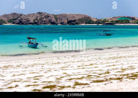 Bateaux dans un océan tropical peu profond à côté d'une plage de sable (Lombok, Indonésie) Banque D'Images