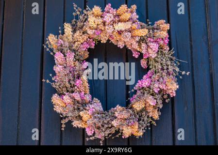 Concept de décoration de la maison, couronne de fleurs séchées accrochée sur la porte d'entrée bleue Banque D'Images