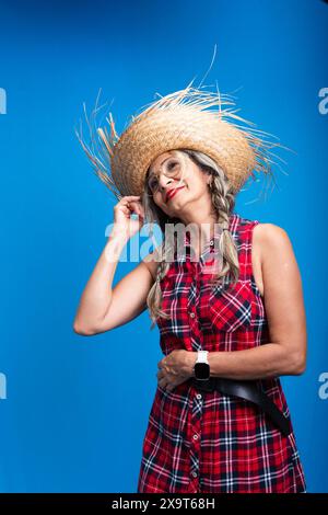 Belle femme habillée pour le festival Sao Joao, debout, avec des tresses dans les cheveux et dansant. Isolé sur fond bleu. Banque D'Images