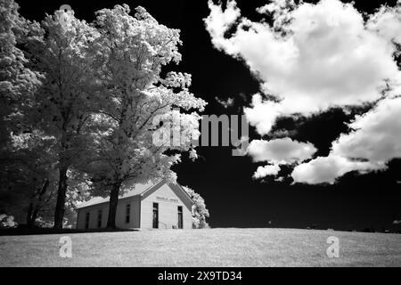 Une image en noir et blanc à contraste élevé d'une petite église de campagne sur une route de campagne dans le sud de l'Indiana. Des nuages moelleux contre un ciel noir déclenchent la scène Banque D'Images