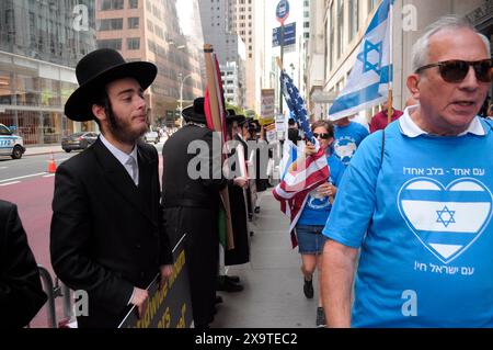 Les membres de Neturei Karta, à gauche, qui sont des juifs ultra-orthodoxes et antisionistes, manifestent dans la rue près des partisans d'Israël, à droite, lors de la 59e parade annuelle de la fête d'Israël. Le défilé de la fête d'Israël, commémorant la culture juive, attire des fêtards, des chars et des organisations israélo-américaines à Midtown Manhattan, New York City. Le défilé a eu lieu près de huit mois après le début de la guerre Israël-Hamas. Le défilé de cette année a porté sur la solidarité israélienne dans la guerre en cours. Le département de police de New York a renforcé la sécurité pour le défilé en raison des inquiétudes liées aux manifestations pro-palestiniennes. Banque D'Images