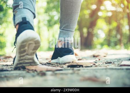 chaussures de sneaker jeune femme voyageur assis sur le parc d'été. Focus sur les chaussures de sneaker et les jeans sur Pathway dans le parc forestier. vacances d'activité active sur hi Banque D'Images