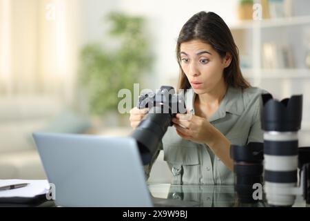 Photographe choqué vérifiant le résultat sur l'appareil photo travaillant à la maison Banque D'Images