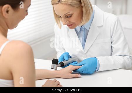 Dermatologue avec dermatoscope examinant le patient à table blanche en clinique Banque D'Images