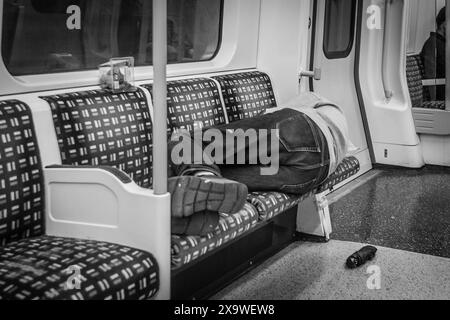 Une image en noir et blanc d'un banlieue faisant une sieste dans le métro à Londres. Banque D'Images