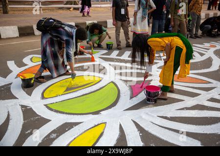 Des étudiants de la Faculté des Beaux-Arts de l'Université de Dhaka peignent des dessins colorés, localement connus sous le nom d'alpona, sur la route en face du Central Shaheed M. Banque D'Images