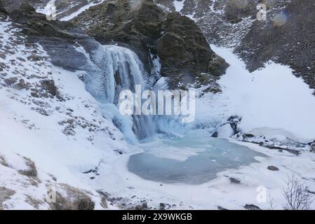 . Cascade Helgufoss couverte de glace au début du printemps. Islande Banque D'Images