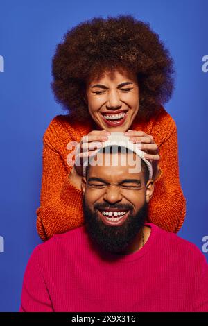 Une jeune femme afro-américaine tenant une tête masculine, à la fois souriante, montrant l'amitié et la connexion. Banque D'Images