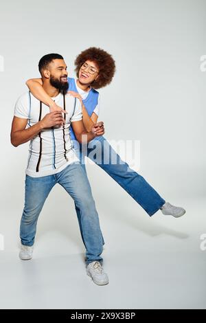 Un homme afro-américain dans des vêtements élégants porte une femme sur son dos, montrant l'amitié et la confiance. Banque D'Images
