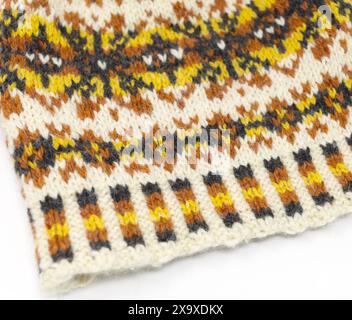 Photographie rapprochée d'un bonnet tricoté en laine tweed Fair Isle en blanc, jaune, orange et noir, bonnet nordique isolé sur fond blanc Banque D'Images