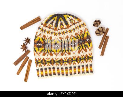 Photographie à plat d'un chapeau tricoté en laine tweed Fair Isle en blanc, jaune, orange et noir sur fond blanc avec décor de cadeaux nature Banque D'Images