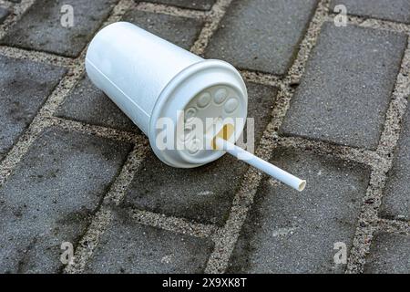 Un gobelet en papier blanc jeté repose sur le sol Banque D'Images