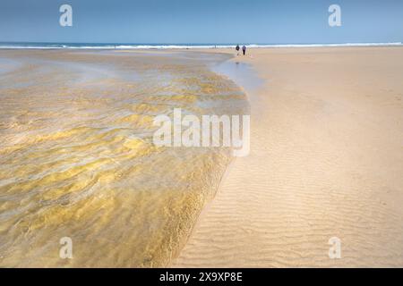 Les gens qui marchent le long de la rivière Menalhyl qui traverse la plage à Mawgan Porth, dans les Cornouailles, au Royaume-Uni. Banque D'Images