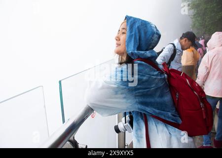 Voyageuse thaïlandaise visite pose portrait prendre une photo sur Glass Walkway ou Canyon Skywalk falaise abrupte dans le parc forestier national de Tianmen sous la pluie Banque D'Images