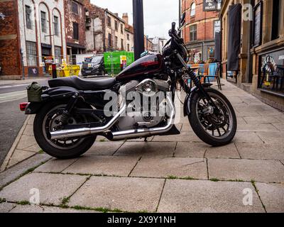 Moto Harley-Davidson garée sur le trottoir à l'extérieur d'un pub dans le centre-ville de Leeds, avec la reconstruction d'un centre-ville en cours derrière. Banque D'Images