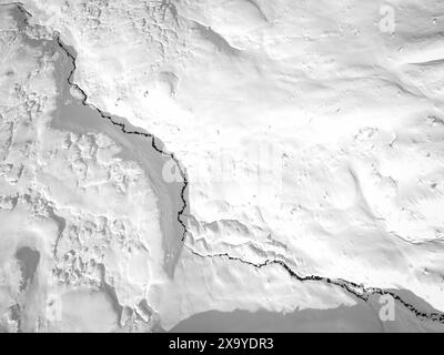 Une vue aérienne d'un petit ruisseau serpente à travers la couverture fraîche de neige. Banque D'Images