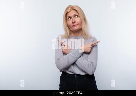 Une femme de 45 ans aux cheveux blonds pointe ses mains sur le côté Banque D'Images