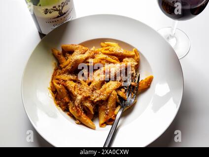 Pâtes Penne avec une sauce bolognaise et un verre de Pinot Noir Banque D'Images