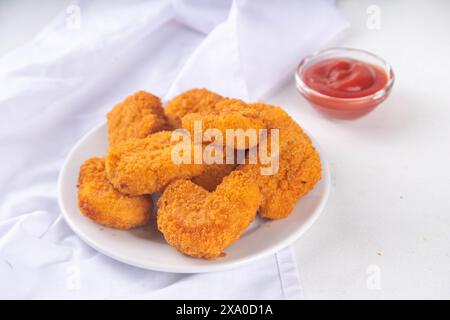 Nuggets de poulet frits dorés traditionnels sur une assiette, avec sauce ketchup. Banque D'Images