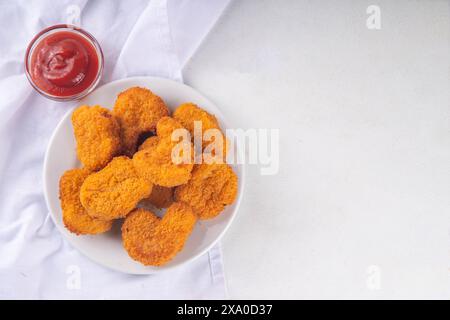 Nuggets de poulet frits dorés traditionnels sur une assiette, avec sauce ketchup. Banque D'Images