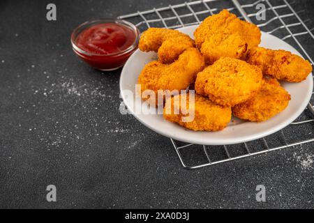 Nuggets de poulet frits dorés traditionnels sur une assiette, avec sauce ketchup. Banque D'Images